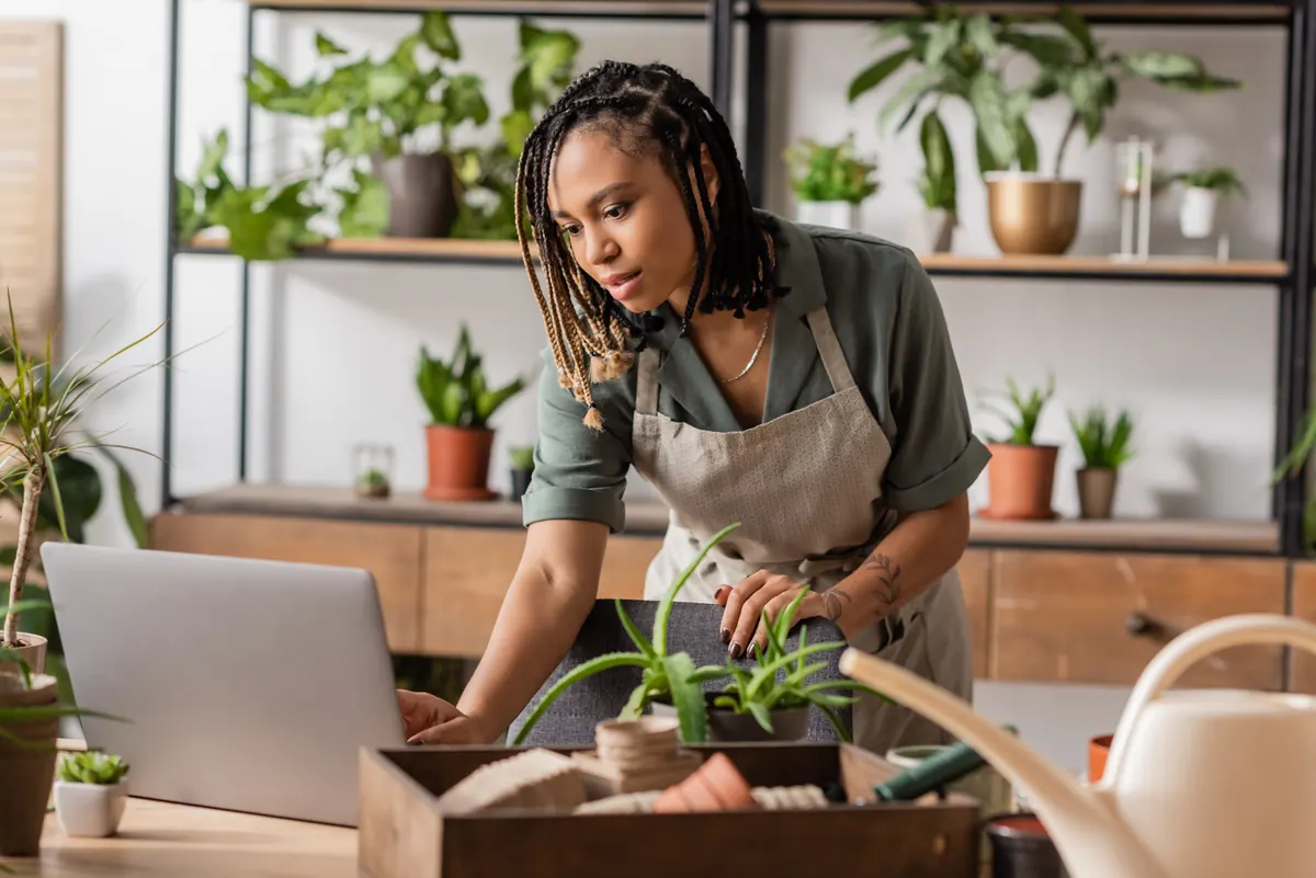 Shop owner working on a laptop at the counter of her plant shop