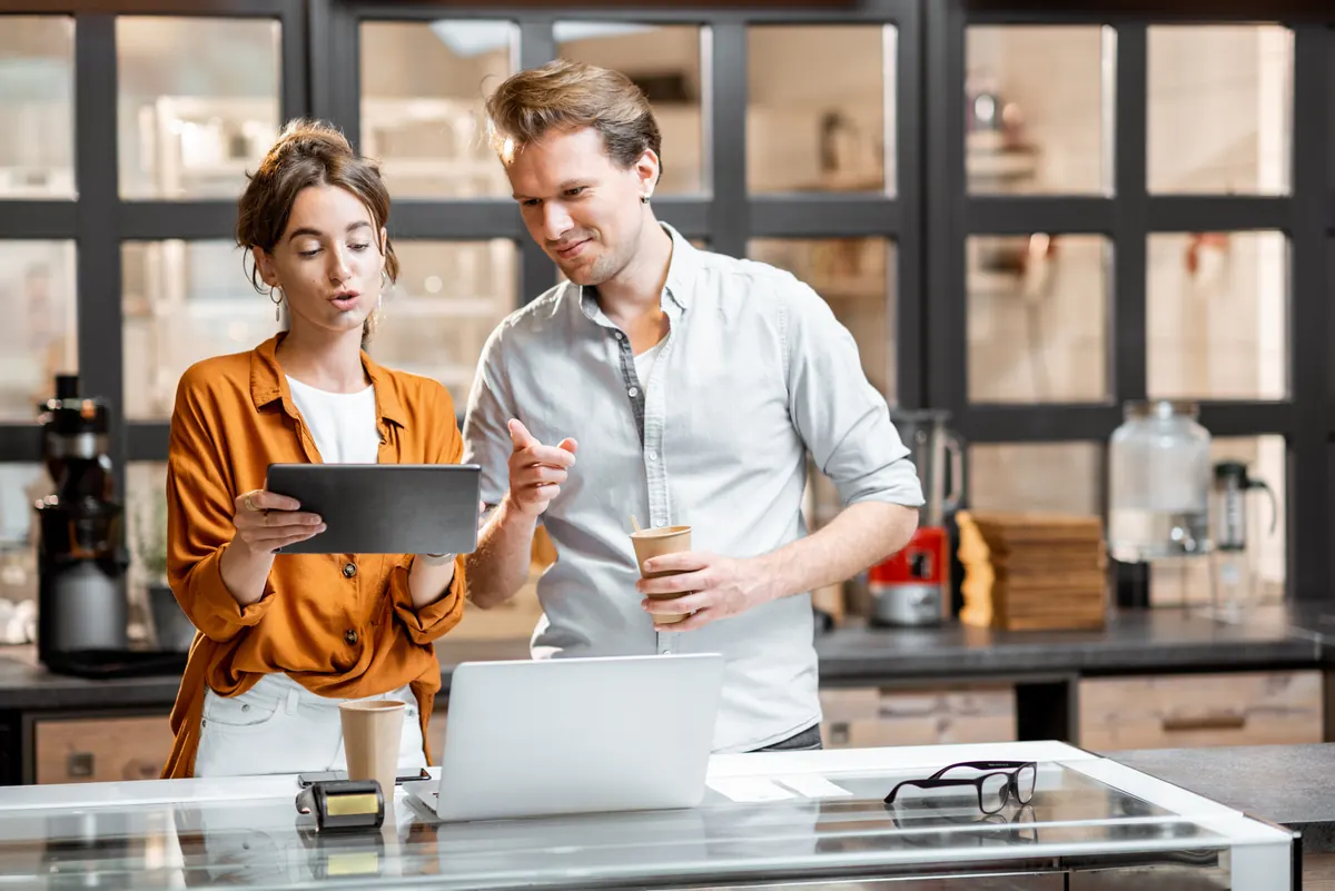 Two business owners reviewing a tablet together at their shop counter